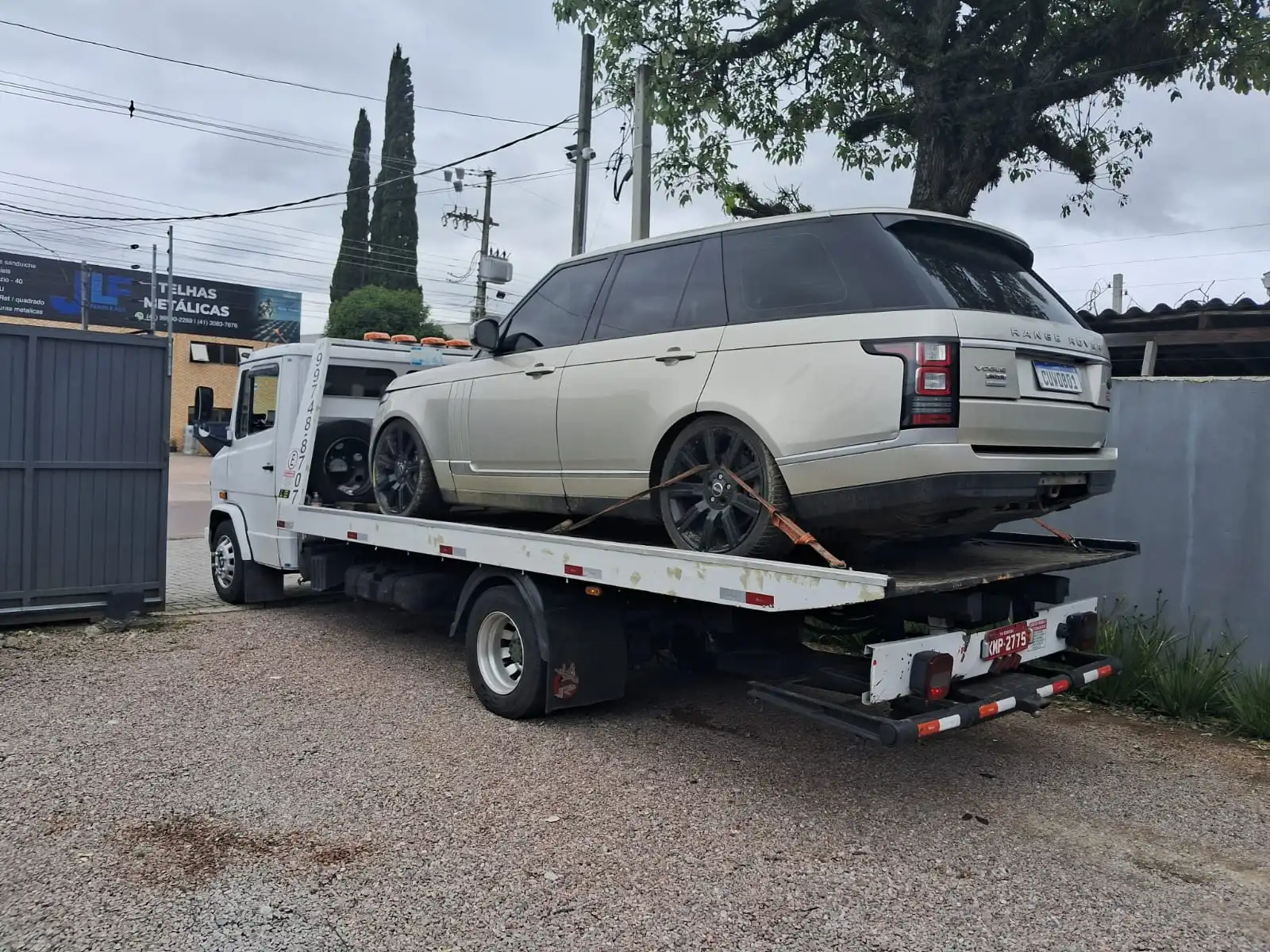 Guincho com carro de grande porte sendo carregado em pátio de oficina